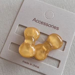 Mini honey yellow resin bow hair clips set on display card over beige fabric background