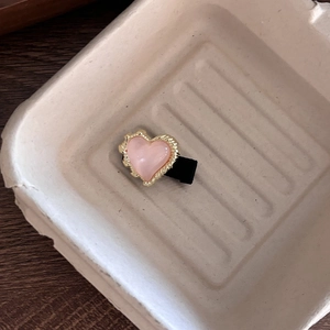 Nahaufnahme einer rosa Herz-Haarklammer mit goldenem Wellenrand und schwarzer Basis
