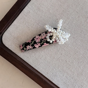 Detail of floral fabric hair clip with beaded pearls and crystals on linen board
