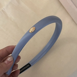 Macro detail of handmade light blue padded headband with golden logo and handmade label