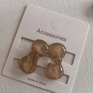 Detail of brown resin bow hair clips on display card with marble texture finish