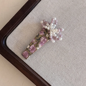 Pastel floral hairpin with purple beads and white pearls on vintage linen background