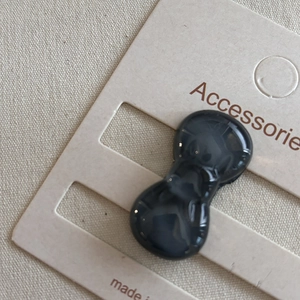 Detail shot of marble pattern peanut-shaped resin hair clip on a display card