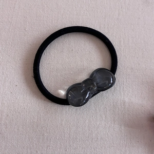 Detail of high-elasticity black hair tie with a dark grey translucent resin bow charm