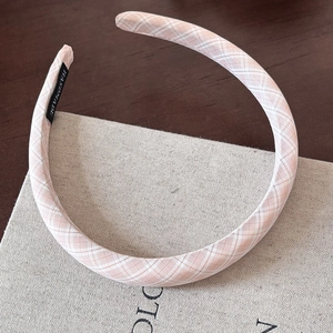 Detail of pink and white checkered fabric headband with black handmade label on side