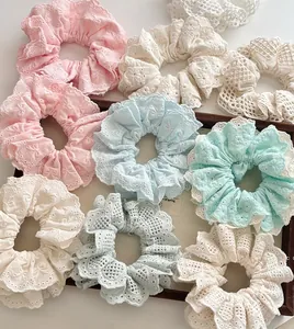 Close-up of handmade lace embroidery scrunchies in pastel colors on a wooden tray