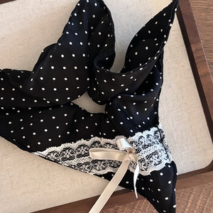 Detail of black polka dot scrunchie featuring white lace trim and a beige silk bow accent