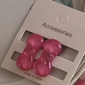 Pair of mini pink resin bow hair clips displayed on a beige card for girls