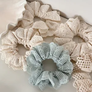 Detailed view of handmade lace embroidery hair scrunchies in blue and cream cotton