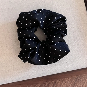 Detailed view of black polka dot lace scrunchie with silk texture and elastic band