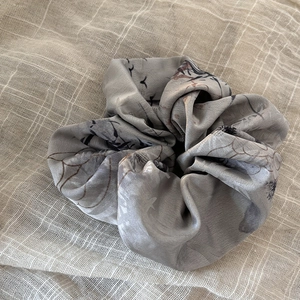Ink wash grey silk scrunchie with bird and floral patterns on linen background