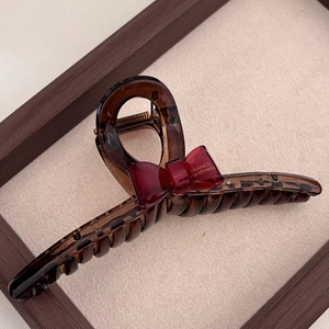 Detail of premium tortoise shell hair claw with red resin bow and handmade logo