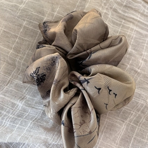 Detailed macro view of silk-like champagne scrunchie with Chinese ink wash mountain print