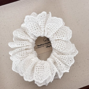 Elegant white lace scrunchie with intricate embroidery and layered ruffle design for hair