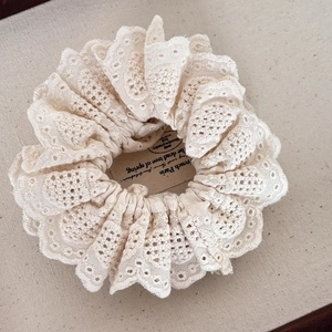 Detailed macro view of the cream white lace scrunchie with intricate floral embroidery texture