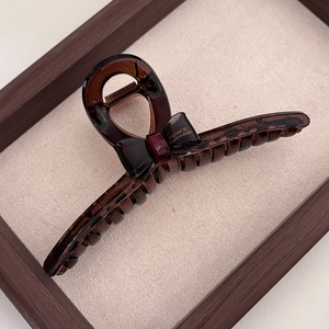 Detailed macro of amber translucent hair claw clip with bow and gold handmade lettering