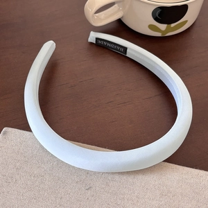 Detail of light blue padded fabric headband with handmade label on wooden table
