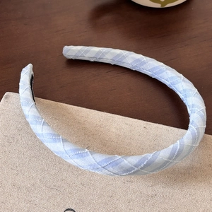 Detailed view of light blue plaid fabric headband with elegant stitched texture