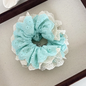 Close-up of double-layer lace scrunchie featuring blue floral embroidery and scalloped edges