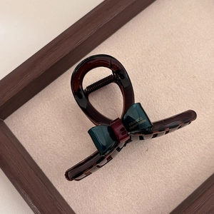 Detail of translucent tortoiseshell hair claw with green ribbon and France Handmade gold text