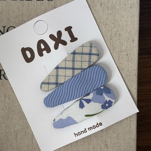 Detailed view of handmade blue patterned chiffon bow hair clips on a display card
