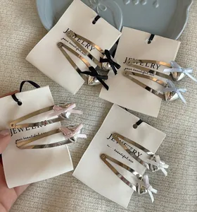 Close-up of heart-shaped silver BB hair clips with satin bows on a display card