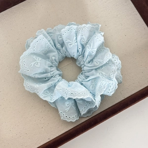 Macro detail of handmade light blue lace scrunchie with delicate butterfly embroidery