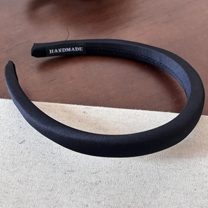 Detailed close-up showing the handmade label on the classic black satin fabric headband