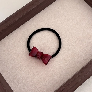 Detail showing the burgundy resin bow hair tie with gold France Handmade lettering