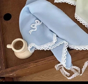 Détail d'un foulard en dentelle bleue avec noeud blanc sur un plateau en bois rétro