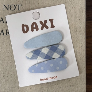 Detailed close-up of a 3-piece blue plaid fabric hair clip set on a white display card