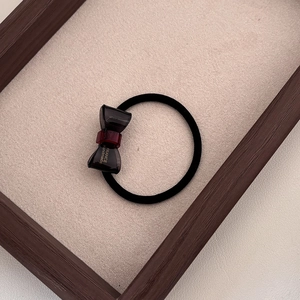 Close-up of handmade resin bow hair tie with elegant gold lettering on wooden frame