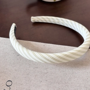 Close-up of the beige and green striped fabric texture on the padded sponge headband