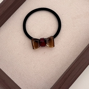 Detailed shot of elastic hair tie with brown resin bow featuring France handmade text