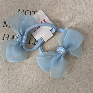 Detail of light blue chiffon bow hair clips with central crystals on rustic linen fabric