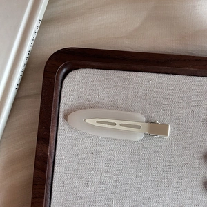 Detailed view of cream matte drop-shaped hair clip on a minimalist display tray