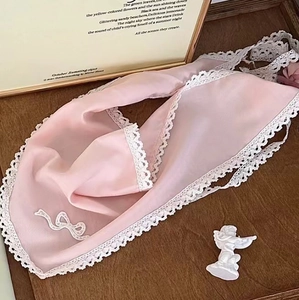 Détail de foulard en mousseline rose pâle avec dentelle blanche et nœud sur plateau