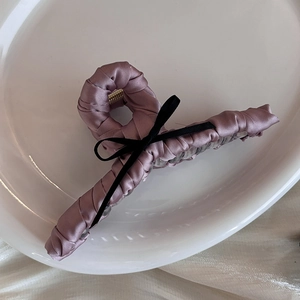 Elegant mauve satin shark hair clip with a small black ribbon bow on a white plate