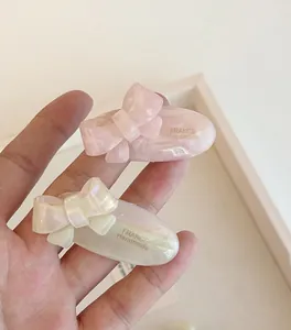Detail of handmade acetate ribbon hair clips in soft pink and iridescent white colors