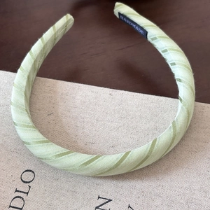 Close-up of handmade green striped padded headband with soft woven fabric texture