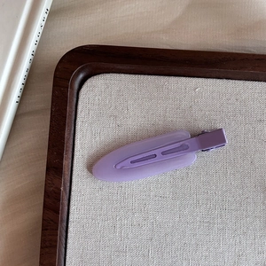 Detail of a matte lavender resin seamless duckbill hair clip on a burlap display tray