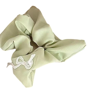 Light green ruffled scrunchie with white lace bow decoration on plain background