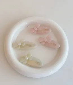 Close-up of four pink and ivory acetate bow hair clips with France Handmade engraving