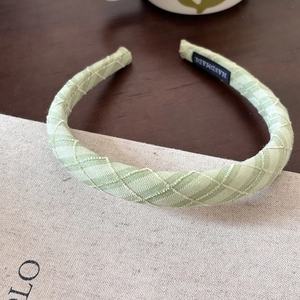 Detail of mint green plaid fabric headband featuring handmade woven label and embroidery
