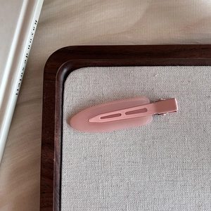 Detail of pink matte resin duckbill hair clip on a minimalist linen and wood tray
