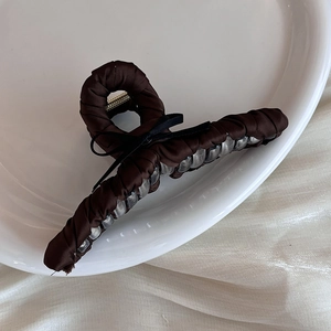 Detailed view of large dark brown satin shark hair claw clip with black ribbon bow