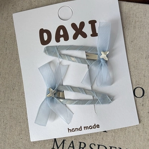 Detailed view of light blue chiffon bow hair clips on a white handmade display card
