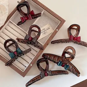 Elegant tortoiseshell claw clip with contrast bow detail set on wooden box display