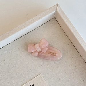 Detail of a handmade pink acetate bow hair clip with a marble texture finish