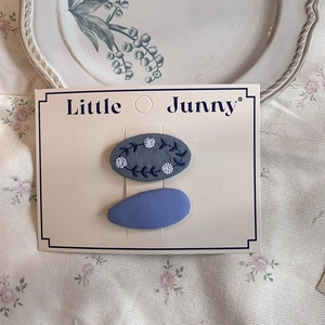 Detailed shot of embroidered floral grey clip and light blue hair pin on display card